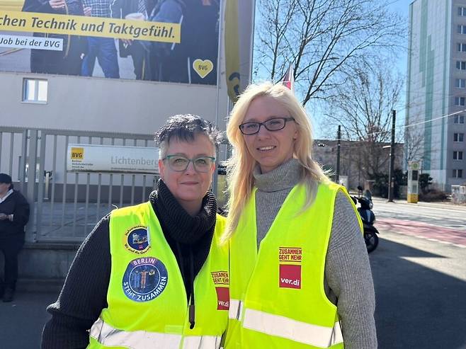 베를린 교통공사 건물이 있는 리히텐베르크 차고지에서 열린 집회에 참여한 재키(왼쪽)와 도레인(오른쪽). 재키가 입은 조끼엔 파업하는 노동자들을 위해 베를린의 일반 시민과 학생, 노동자가 연대하는 ‘함께하는 베를린’ 스티커가 부착돼 있다. 사진 장예지 특파원