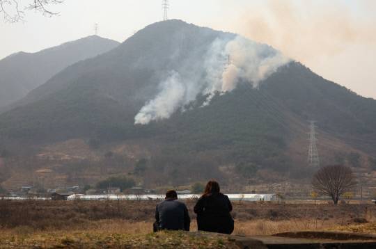 경남 산청군에서 발생한 산불 사흘째인 23일 단성면 일대에 산불이 마을 쪽으로 향하자 주민들이 걱정스럽게 바라보고 있다. 연합뉴스