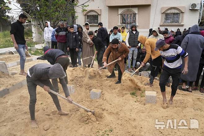 [칸유니스=AP/뉴시스] 3월 20일 가자지구 남부 칸유니스에서 팔레스타인 주민들이 이스라엘군의 나세르 병원 공습으로 숨진 희생자들의 시신을 집단 매장하고 있다. 2025.03.25.