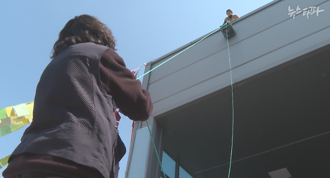 경북 구미시 구포동 외국인투자지역에 입주해 있는 ‘한국옵티칼하이테크’ 공장에서 지난 3월 19일 금속노조 한국옵티칼하이테크지회 이지영 사무장이 공장 옥상에서 농성을 벌이고 있는 박정혜 씨에게 식사를 전달하고 있다.