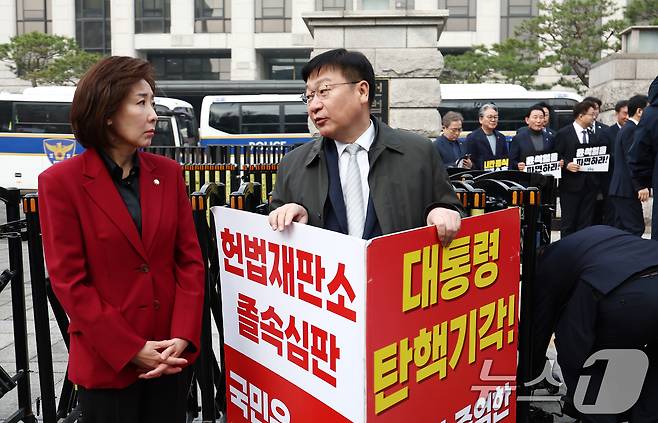 국민의힘 나경원 의원과 정점식 의원이 25일 오전 서울 종로구 헌법재판소 앞에서 윤석열 대통령 탄핵 반대 1인 시위를 하며 대화하고 있다. 오른쪽은 더불어민주당 의원들이 윤 대통령 파면 촉구 피켓을 들고 있는 모습. 2025.3.25/뉴스1 ⓒ News1 김민지 기자
