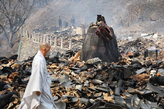 A monk walks past the ruins of Gounsa, a Buddhist temple in Uiseong County, North Gyeongsang, on March 26. The temple was burned to the ground by the wildfires currently ravaging southeastern Korea.