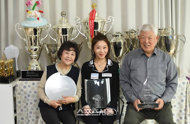 프로당구 우승트로피를 배경으로 과거 포켓 선수 시절 우승컵을 들고 포즈하는 김가영 가족.