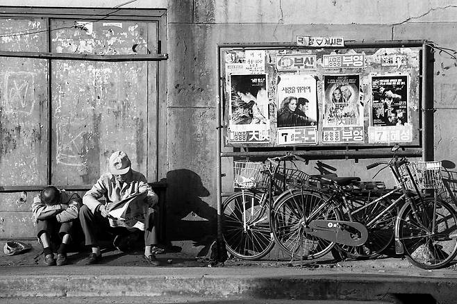 1991년 남포동 자갈치시장 주변 극장게시판 옆에서 한 남성이 신문을 보고 있다./ 사진가 문진우