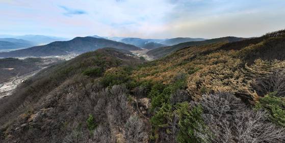 27일 경북 지역에서 6일째 번지고 있는 산불의 최초 발화 지점인 의성군 안평면 괴산리 한 묘소 인근에 폴리스라인이 설치된 가운데 주변 산림이 폐허가 된 모습을 보이며 먼 산에서 산불 연기가 피어오르고 있다. 연합뉴스