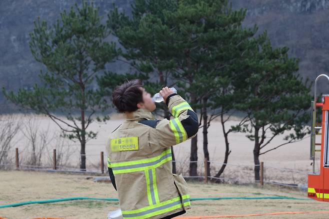 A firefighter hydrates on the job as he protects the Byeongsanseowon Confucian academy in Andong, North Gyeongsang Province, Friday. (Yonhap)
