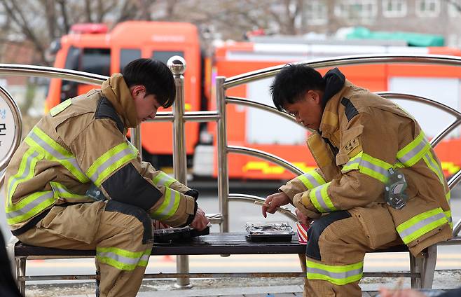 Firefighters dispatched to Uiseong-gun, North Gyeongsang Province, take a break to eat lunch on Friday. (Yonhap)