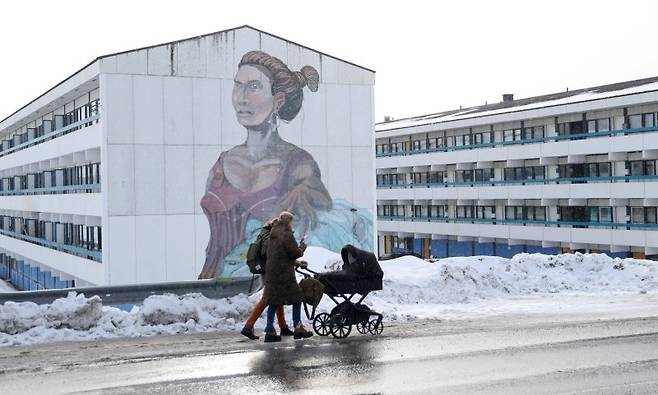 27일(현지시간) 그린란드 누크에서 지역 시민들이 이누이트 벽화가 그려진 사회 주택이 있는 건물을 지나가고 있다. 로이터 연합뉴스