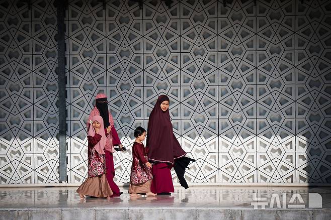 [쿠알라룸푸르=AP/뉴시스] 31일(현지 시간) 말레이시아 쿠알라룸푸르의 국립 모스크 마스지드 느라그에서 이드 알피트르 기도를 마친 무슬림 여성들이 어린이와 함께 사원을 떠나고 있다. 2025.03.31.