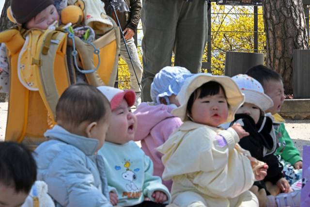 기온이 큰 폭으로 오르며 평년 수준을 회복한 31일 서울 성동구 응봉산에서 트래킹 모임 어머니들과 함께 온 아이들이 노랗게 핀 개나리 앞에 앉아 있다.