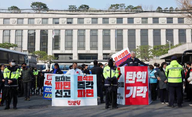 윤석열 대통령 탄핵심판 심리가 4월로 넘어온 1일 서울 종로구 헌법재판소 앞에서 국민의힘과 더불어민주당, 진보당 관계자들이 손팻말을 들고 1인 시위를 하고 있다.연합뉴스
