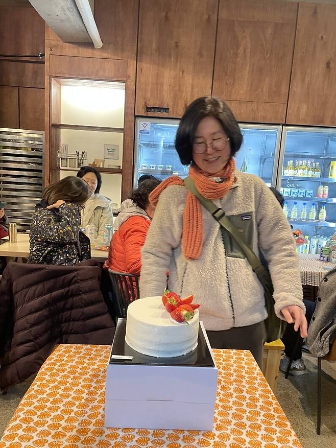 콩풀이 자랑한 케이크를 바라보며 흐뭇하게 웃고 있는 김소민 은모래마을책방 지기.