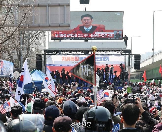 윤석열 대통령 탄핵 선고일인 4일 오전 서울 한남동 대통령 관저 입구에서 윤 대통령 지지자들이 헌재 선고 생중계를 보고 있다. 성동훈 기자