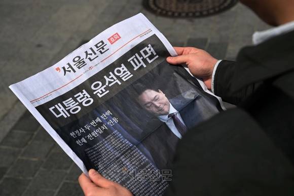 윤석열 대통령이 파면된 4일 오후 서울 중구 시청역 인근에서 시민들이 윤 대통령 파면 관련 서울신문 호외를 읽고 있다. 2025.4.4 오장환 기자
