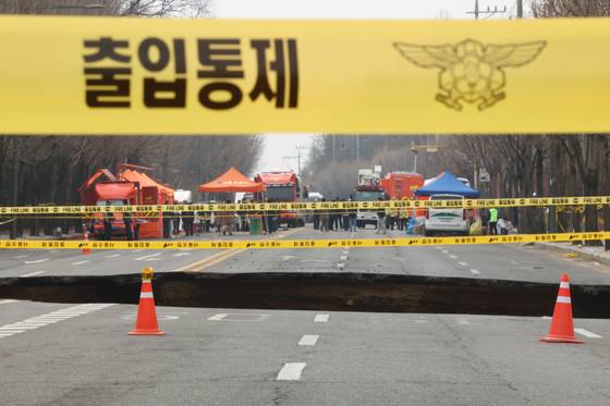 지난달 24일 강동구 명일동 도로에서 전날 발생한 대형 싱크홀 현장에 소방의 출입 통제 라인이 설치돼 있다. 〈출처 : 연합뉴스〉