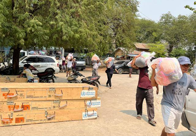 지난 4일 미얀마 만달레이 인근 소도시 아마라푸라의 한 병원에서 시민들이 구호물자가 담긴 봉투를 트럭에서 내려 병원 내부로 옮기고 있다. 왼쪽 아래로 세계보건기구(WHO)가 지원한 물품 상자도 보인다. 아마라푸라=허경주 특파원