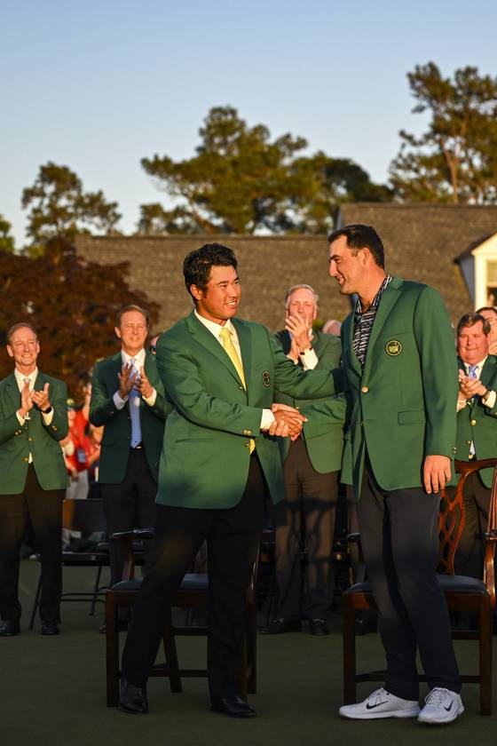 Scottie Scheffler shakes hands with Hideki Matsuyama after receiving the Green Jacket following his three stroke victory following the final round of the Masters Tournament at Augusta National Golf Club in Augusta, Georgia on April 10, 2022.  [GETTY IMAGES]