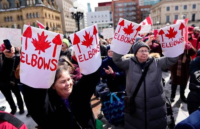 3월 9일 오타와에 있는 캐나다 국회의사당 앞에서 팔꿈치를 위로 들고 집회를 벌이는 트럼프 반대 시위대의 모습. AP 뉴시스