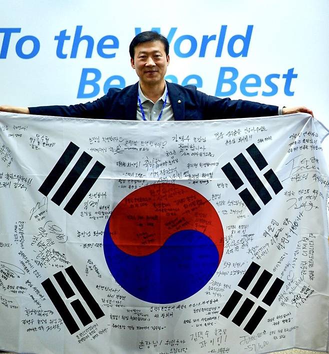 선수·지도자 사인이 담긴 태극기를 들어 보인 김택수 선수촌장 [촬영 이동칠]