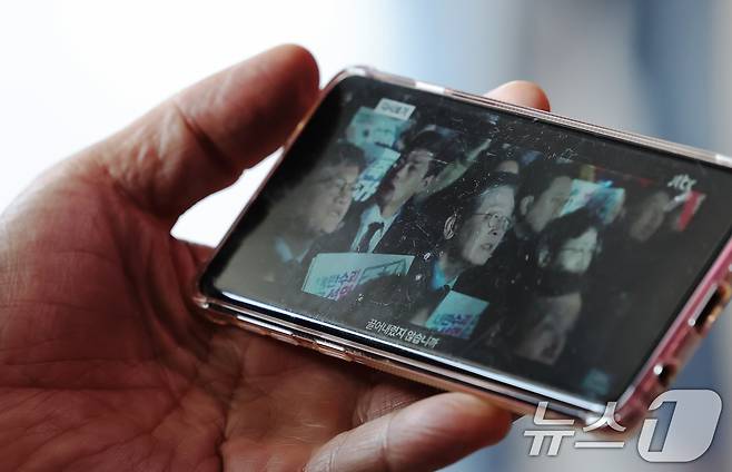 10일 오전 서울 중구 서울역을 찾은 시민이 스마트폰을 통해 이재명 전 더불어민주당 대표의 대통령 선거 출마 선언 영상을 바라보고 있다. 2025.4.10/뉴스1 ⓒ News1 장수영 기자