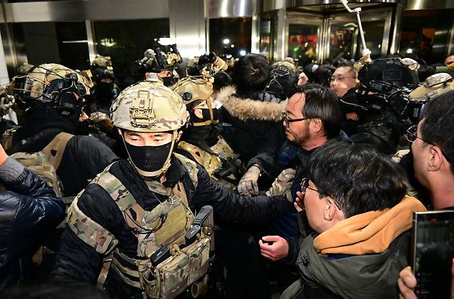 Martial law troops confront parliamentary staff, journalists and other concerned citizens blocking them with their bodies and fire extinguishers from storming the main chamber of the National Assembly the night of Dec. 3. (The Korea Herald/ Lee Sang-sub)