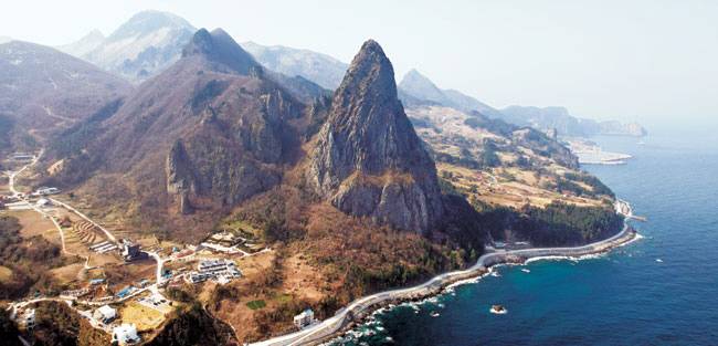 울릉도 북쪽 해안가에 뾰족하게 솟은 송곳산(錐山·추산). 송곳산 아래 보이는 흰색 건물이 리조트단지 코스모스 울릉도의 새로운 공간인 ‘빌라 쏘메’다. 오는 5월 문을 연다.
