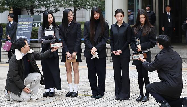 The bandmates of NewJeans respond to reporters' questions as they leave the Seoul Central District Court on March 7. They appeared for a hearing on Ador’s injunction request filed in January to maintain management rights over the group and prevent them from independently signing advertising contracts. (Yonhap)