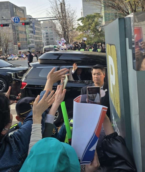 윤석열 전 대통령을 태운 검정색 카니발 차량이 11일 오후 5시 30분쯤 서울 서초구 서초동 아크로비스타 단지로 진입하고 있다. 윤 전 대통령이 창문을 내리고 지지자들에게 손을 흔들고 있다.