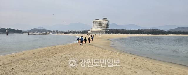 ▲ 최북단 고성군 죽왕면 송지호 해변과 무인도 대섬을 연결하는 바닷길이 열려 눈길을 끌고 있다. 고성지역의 봉사단체인 ‘맨발행복’ 회원들이 밀려든 해양쓰레기를 치우고 난 후 열려 있는 모래톱을 이용해 송지호 해수욕장으로 돌아가고 있다.