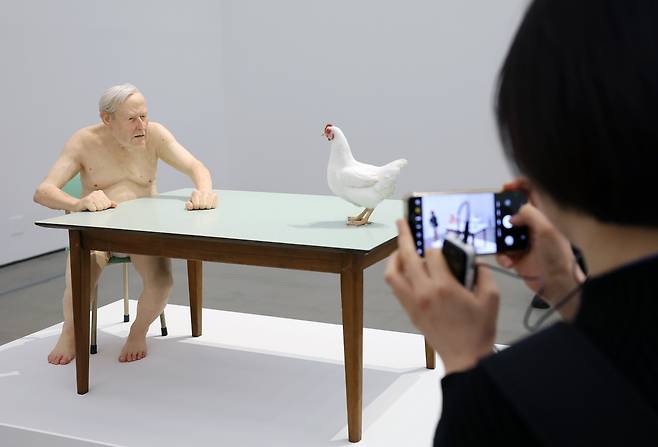 노인과 암탉이 테이블에서 팽팽하게 기싸움을 하고 있는 ‘치킨/맨’(2019). 뉴질랜드 크라이스트처치 아트 갤러리 테 푸나 오 와이훼투 컬렉션. /뉴스1