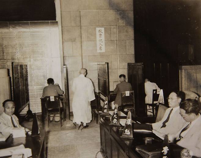 1948년 7월 20일 정·부통령을 선출하기 위해 투표 기입석에서 투표를 하는 제헌 의원의 모습. 오른쪽 자리에 앉은 사람은 장면, 이윤영 의원. /국사편찬위원회