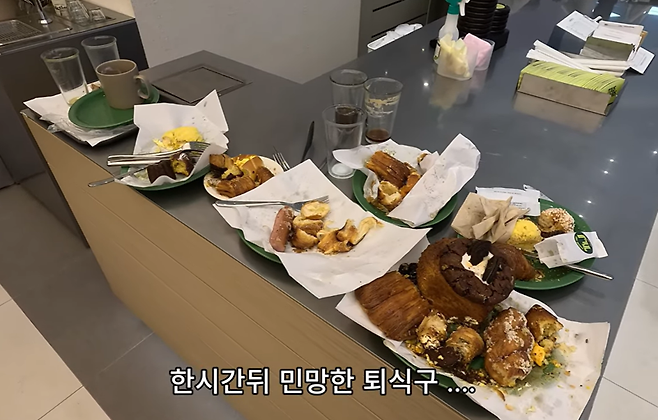 퇴식구에 쌓인 한 입씩만 먹고 남긴 빵이 가득한 접시들/사진=유튜브 '독거또랭이' 캡처