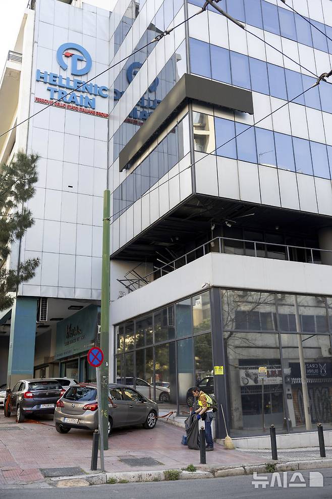 [아테네= AP/뉴시스] 그리스의 철도회사 헬레닉 트레인 본사에서 4월 11일 폭탄이 폭발해 일부 피해가 발생한 다음 날 인부들이 빌딩 외부를 청소하고 있다. 이 사고로 사상자는 없었지만 철도 참사로 철도회사와 정부에 불만을 품은 신세대 테러 단체의 등장에 관심이 집중되었다. 2025. 04. 14.