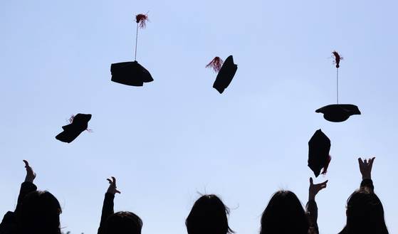 Ewha Womans University graduates toss their caps into the air in Seodaemun District, western Seoul, on Feb. 24. [NEWS1]