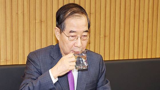 한덕수 대통령 권한대행 국무총리가 16일 결식 아동들에게 무료 점심을 제공해온 울산 뚠뚠이 돈가스에서 사장과 직원들을 격려한 후 물을 마시고 있다. 연합뉴스