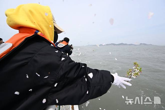 [진도=뉴시스] 김혜인 기자 = 세월호 참사 11주기인 16일 오전 전남 진도군 맹골수도에서 열린 선상추모식 중 세월호 참사 유족이 희생자를 기리며 벚꽃을 바다에 던지고 있다. 이 꽃은 희생자들이 다닌 단원고등학교 교정에 핀 벚꽃이다. 2025.04.16. hyein0342@newsis.com