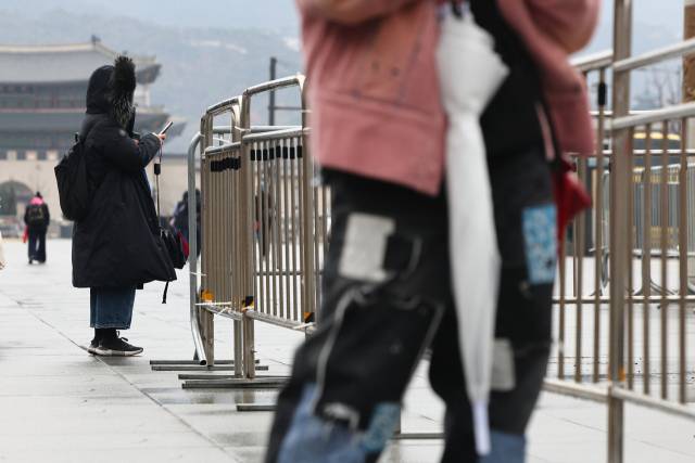 16일 서울 종로구 광화문 광장에서 외투 모자를 쓴 시민이 서 있다. 연합뉴스