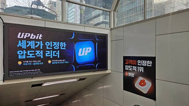17일 서울 지하철 강남역 5번 출구 정면에는 업비트, 측면에는 빗썸의 광고가 각각 올라온 모습. ⓒ데일리안 황지현 기자