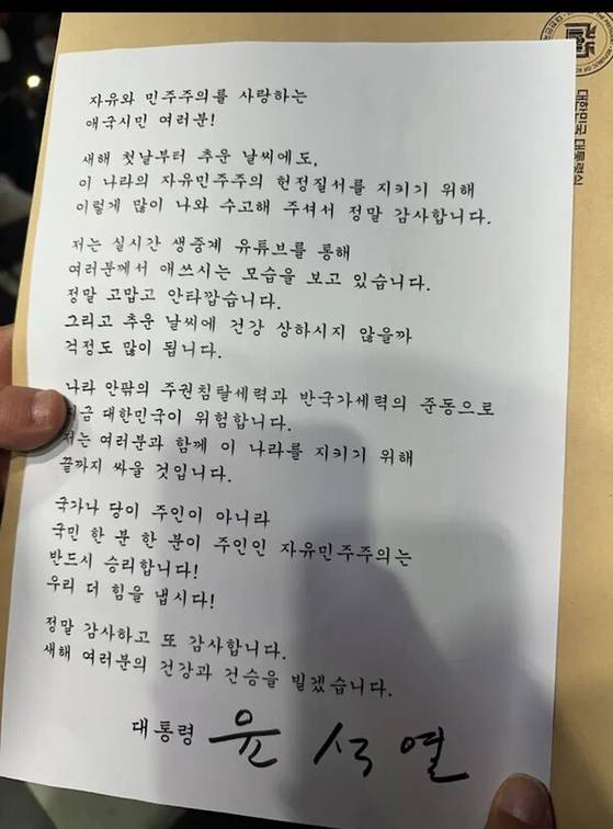 윤 전 대통령은 지난 1월 1일 서울 용산구 한남동 대통령 관저 앞에서 철야집회를 하는 지지자들에게 직접 서명한 새해 인사 및 감사 인사글을 전했다. [뉴시스]