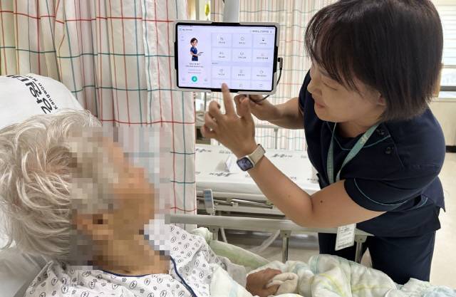 ▲ 강원대학교병원이 국내 최초로 암 환자 간호를 위한 인공지능(AI) 보조시스템을 도입, 간호사가 환자에게 사용법을 설명하고 있다.  강원대병원 제공