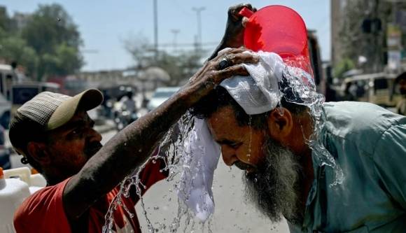 2025년 4월 5일, 파키스탄 남부 카라치에서 자원봉사자가 행인의 머리에 물을 뿌려 더위를 식혀주고 있다. AFP 연합뉴스