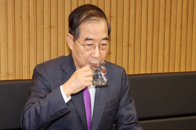 한덕수 대통령 권한대행 국무총리가 16일 결식 아동들에게 무료 점심을 제공해온 울산 뚠뚠이 돈가스에서 사장과 직원들을 격려한 후 물을 마시고 있다. 연합뉴스