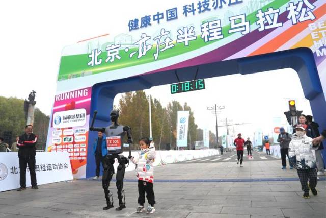 2024년 개최된 베이징 이좡 하프 마라톤 대회에 참가한 휴머노이드 로봇이 어린이와 함께 포즈를 취하고 있다. 바이두 캡쳐