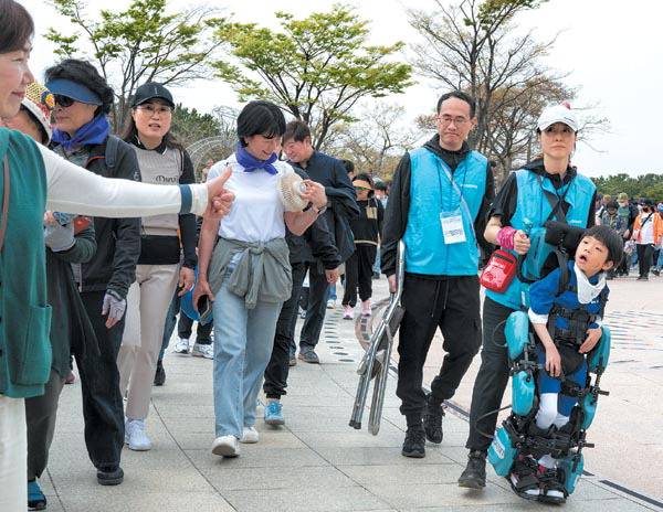지난 19일 부산 사하구 다대포해수욕장 일원에서 부산지역 장애인복지관 연합 장애인식개선 캠패인 ‘제12회 담쟁이 걷기대회’가 열렸다. ‘재활로봇’을 착용하고 참가한 이도윤 군에게 다른 참가자가 엄지를 들어올리며 응원하고 있다.   전민철 기자 jmc@kookje.co.kr