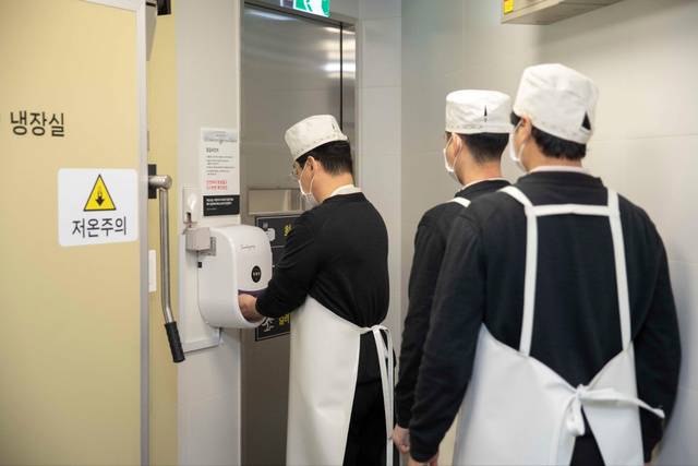 직원들이 조리·소분실로 들어가기 위해 비접촉 자동 손 소독 시스템을 이용하고 있다. 신세계백화점 제공