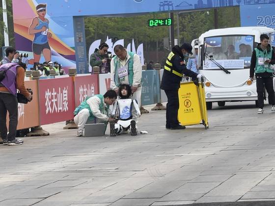 출발하자마자 넘어져 파손된 환환 로봇의 상태를 스텝이 살펴보고 있다. [사진 이좡마라톤]