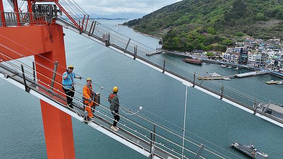 지난 19일 한국 최초 현수교인 경남 남해대교에서 열린 '브리지 클라이밍' 행사에 참여한 기자(가운데)가 내려오며 울상을 짓고 있다. 사진 남해군