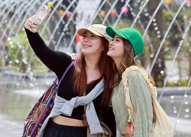 서울의 낮 최고기온이 20도를 기록하는 등 완연한 봄날씨를 보인 18일 오후 서울 종로구 광화문광장을 찾은 외국인이 분수 터널을 배경으로 추억을 남기고 있다.(사진은 기사 내용과 무관.)/사진=뉴스1