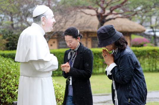22일 오전 충남 서산시 해미국제순교성지 프란치스코 교황의 조형물 앞에서 천주교 신자들이 장대비를 맞으며 고인을 애도하고 있다. 김영태 기자
