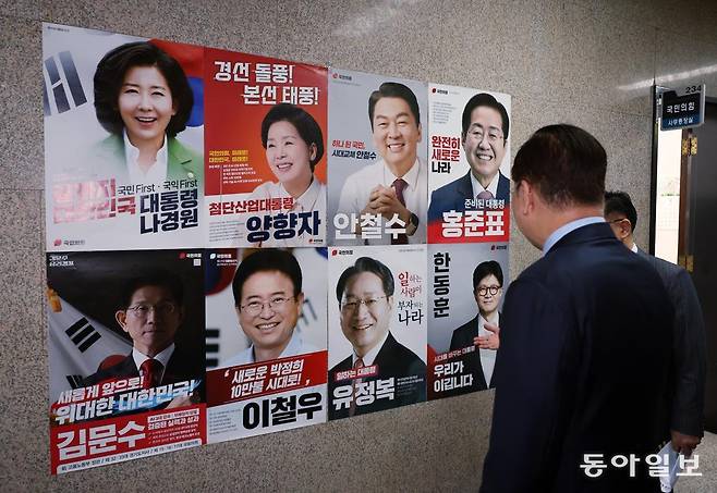 국민의힘 권영세 비상대책위원장이 21일 서울 여의도 국회에서 열린 비상대책위원회의에 참석하며 대선 경선 후보 8명의 얼굴 사진과 슬로건 등이 담긴 포스터를 살펴보고 있다. 국민의힘은 100% 국민여론조사를 통해 8명 중 2차 경선 진출자를 4명으로 압축한 뒤 22일 발표할 예정이다. 장승윤 기자 tomato99@donga.com